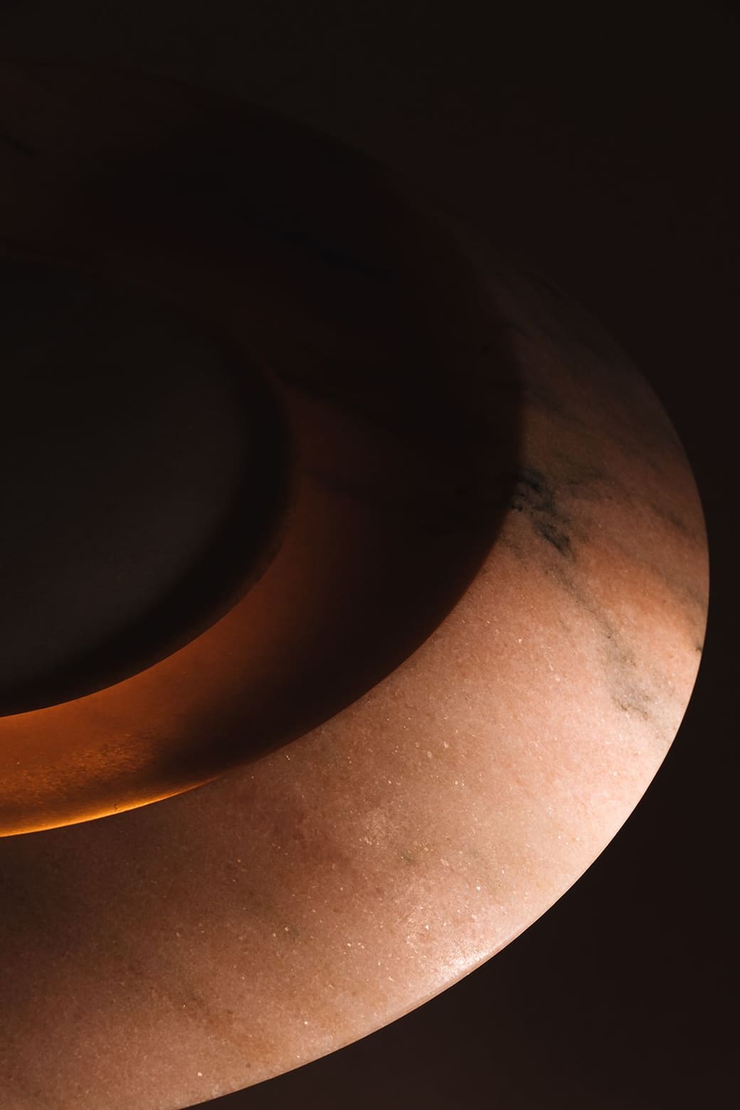 Detail of the FIORE lamp in pink Estremoz Rosa marble, glowing at the centre