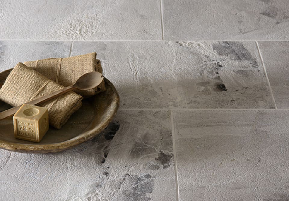 Sandblasted grey stone floor tiles with a wooden bowl